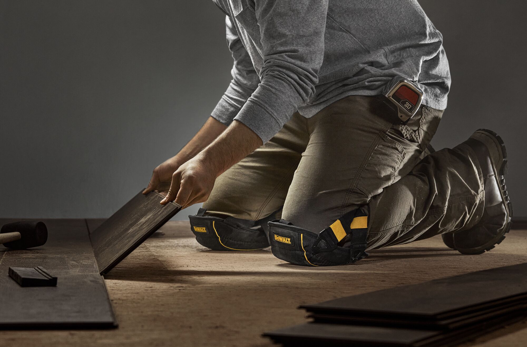 CONSTRUCTION PRO WEARING DEWALT FLOORING KNEE PADS WITH GEL WHILE