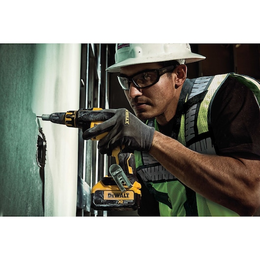 DEWALT class 2 heavy duty surveyor vest being worn by a person using a powertool.
